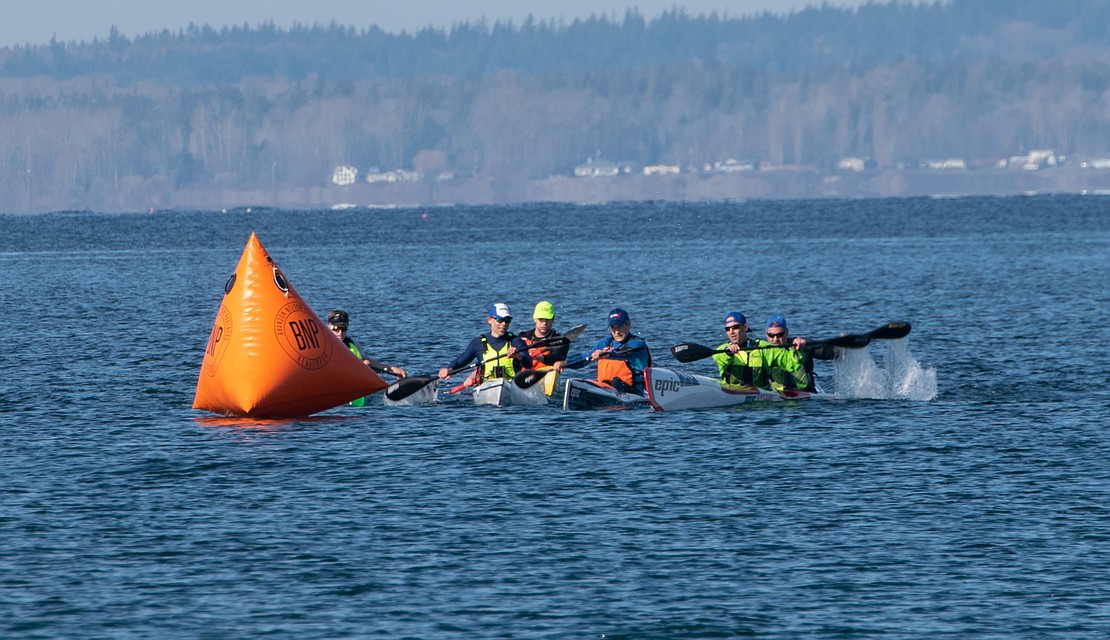 A mix of doubles and singles high-performance kayakers jockey for a spot as they round a buoy.