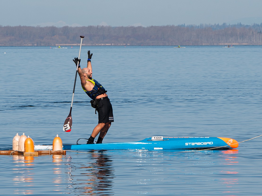 Waleed Ammar throws his hands into the air after crossing the finish line of the Peter Marcus Rough Water Race in Fairhaven.