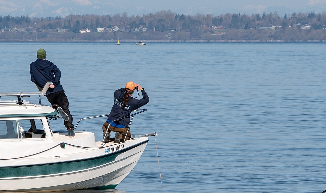 Race director Kevin Olney looks through binoculars to read bib numbers on incoming watercraft.