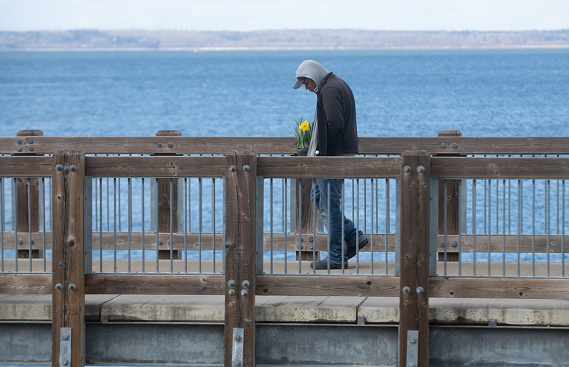 Jay Clark carries flowers March 25 across Taylor Dock to a memorial for Henry King.