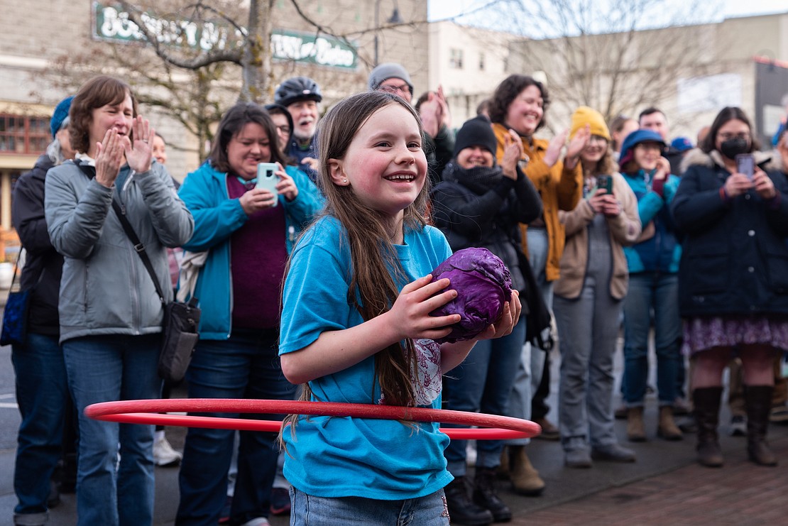 Avelene smiles and hula hoops as she catches a cabbage from Bellingham Mayor Seth Fleetwood.