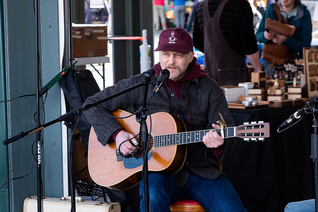 Devin Champlin of Champlin Guitars sings during the beginning of the market.