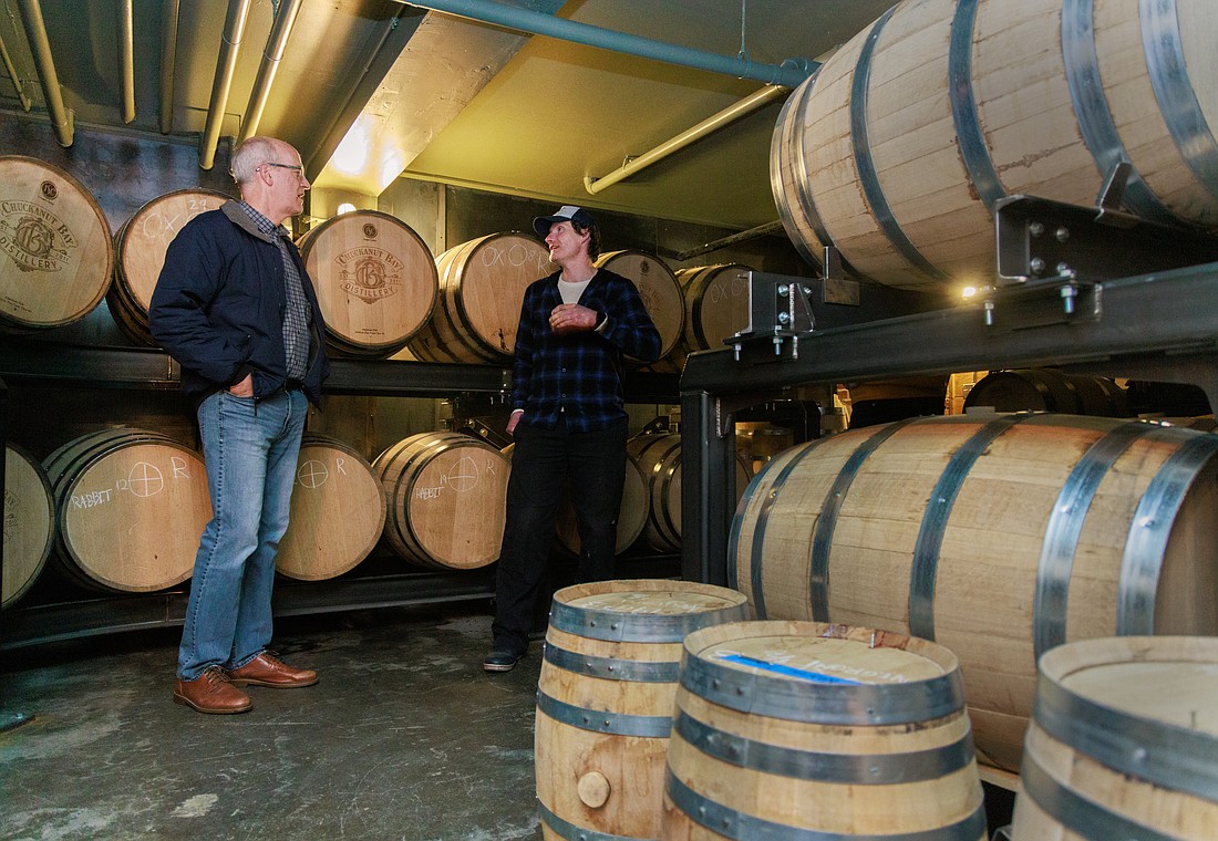 Surrounded by barrels of bourbon and rye whiskey, U.S. Rep. Rick Larsen talks with Chuckanut Bay Distillery co-owner Matt Howell during an April 7 tour in Bellingham.