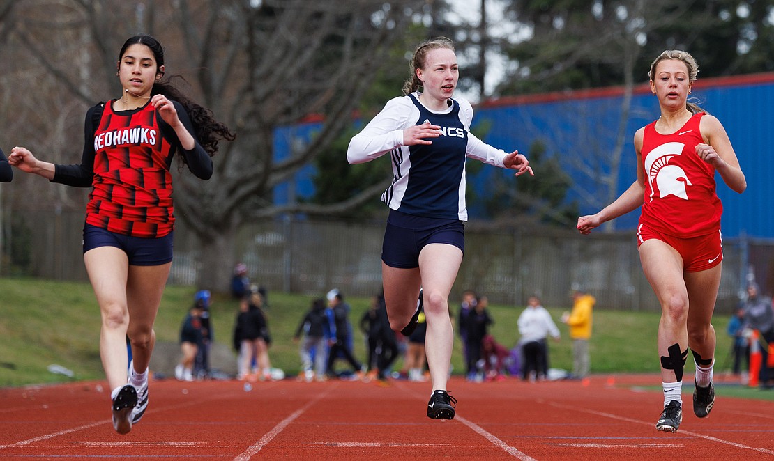 Lynden Christian's Josie Hendricks, center, looks over at the timer as she finishes first in her heat of the girls 100-meter dash April 8 at the Birger Solberg Invitational track meet at Civic Stadium.