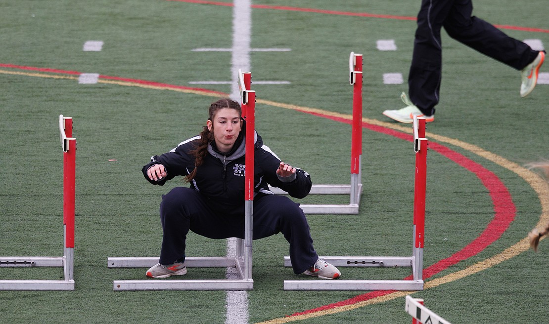 Getting ready for her race, Nooksack Valley's Emily Perry ducks under a series of hurdles as she warms up.