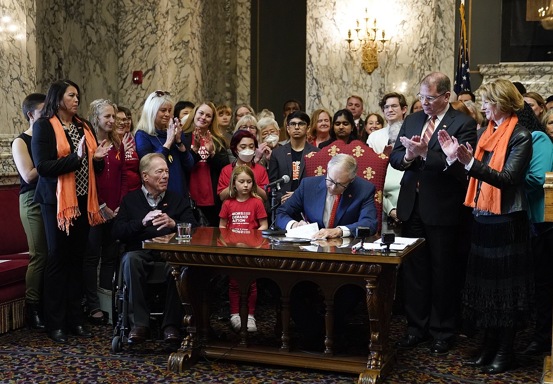 Washington Gov. Jay Inslee signs House Bill 1240 April 25 at the Capitol in Olympia, which prohibits the manufacture, importation, distribution and sale of semi-automatic assault-style weapons in the state. Rep. Strom Peterson, D-Edmonds, the bill's primary sponsor, and Sen. Patty Kuderer, D-Bellevue, look on at right.