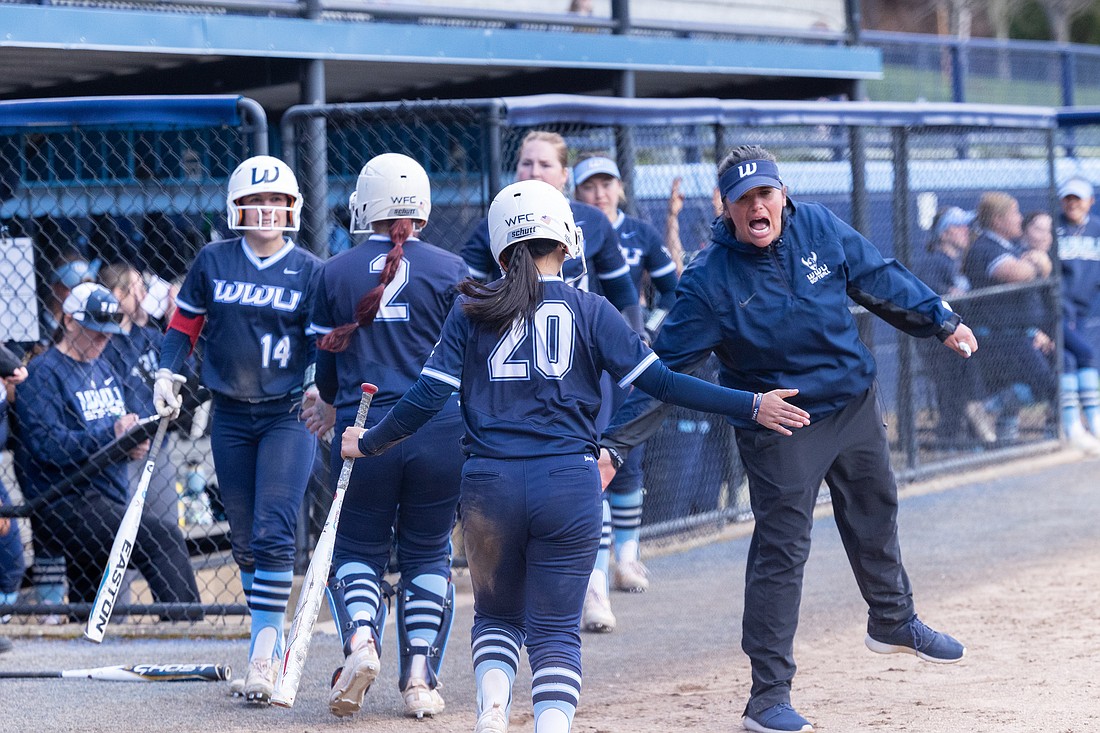 Western Washington University softball coach Sheryl Gilmore, right, excitedly welcomes players back to the dugout March 27 during a doubleheader with Western Oregon at Viking Field.