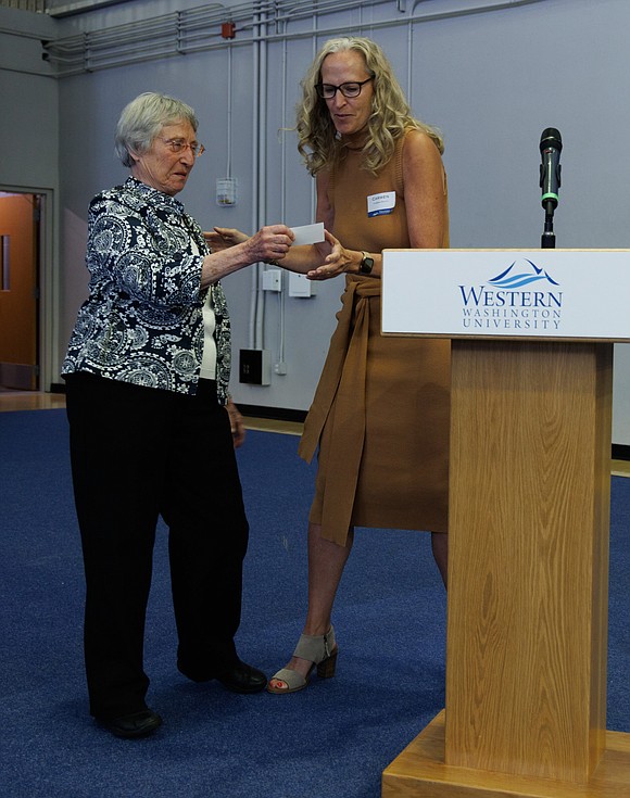 Former, and first, Western Washington University women’s basketball coach Evelyn Ames hands off her name card to current head coach Carmen Dolfo before receiving her varsity letter from the university.