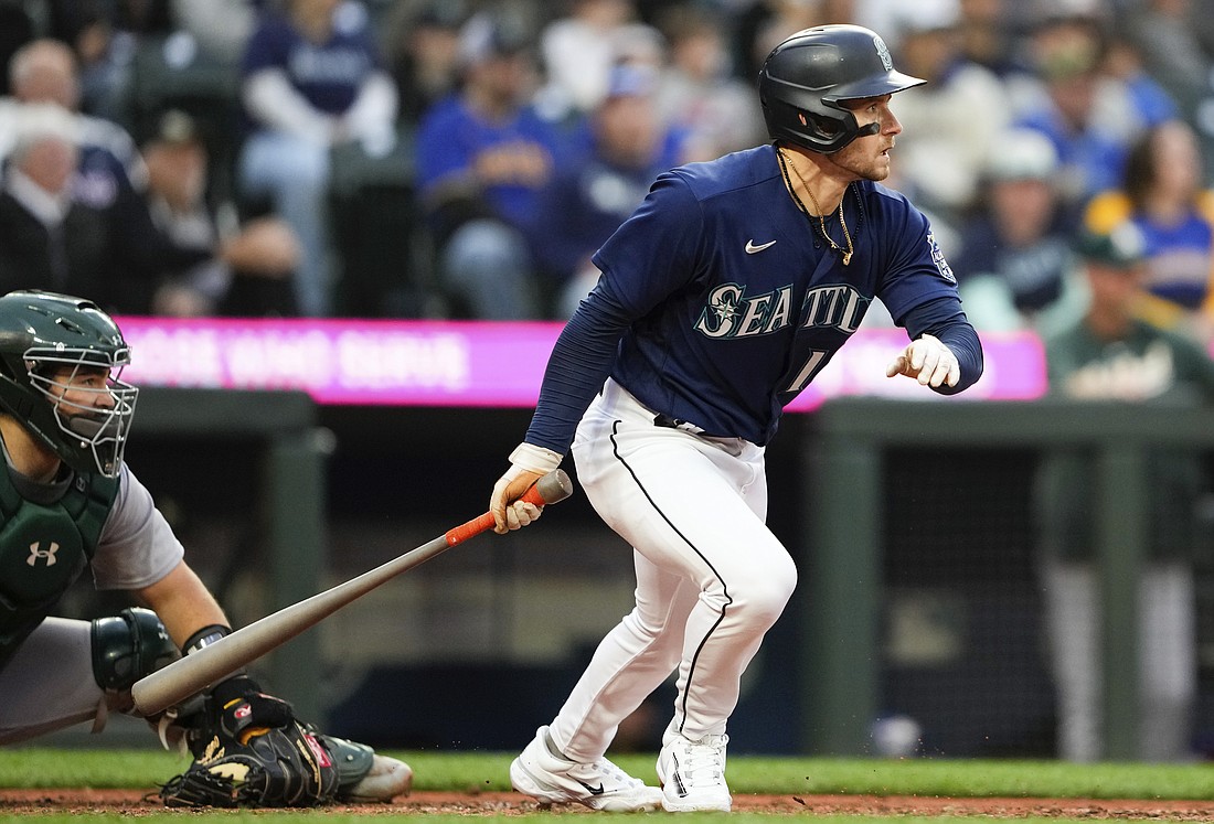 Seattle Mariners' Jarred Kelenic, right, follows through on an RBI-single as Oakland Athletics catcher Shea Langeliers, left, looks on during the fifth inning of a baseball game Monday, May 22, 2023, in Seattle.