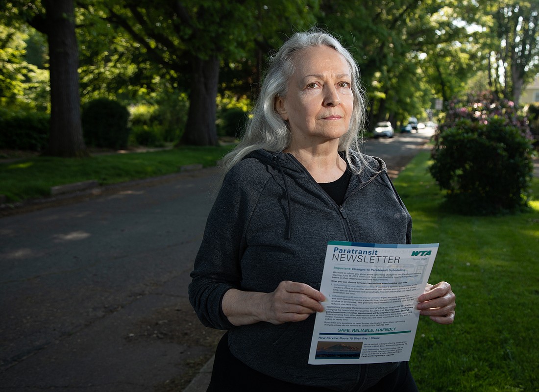 Linda Joy De Long holds a newsletter from Whatcom Transportation Authority about changes that would no longer allow paratransit users to call for a pickup after finishing their errands.