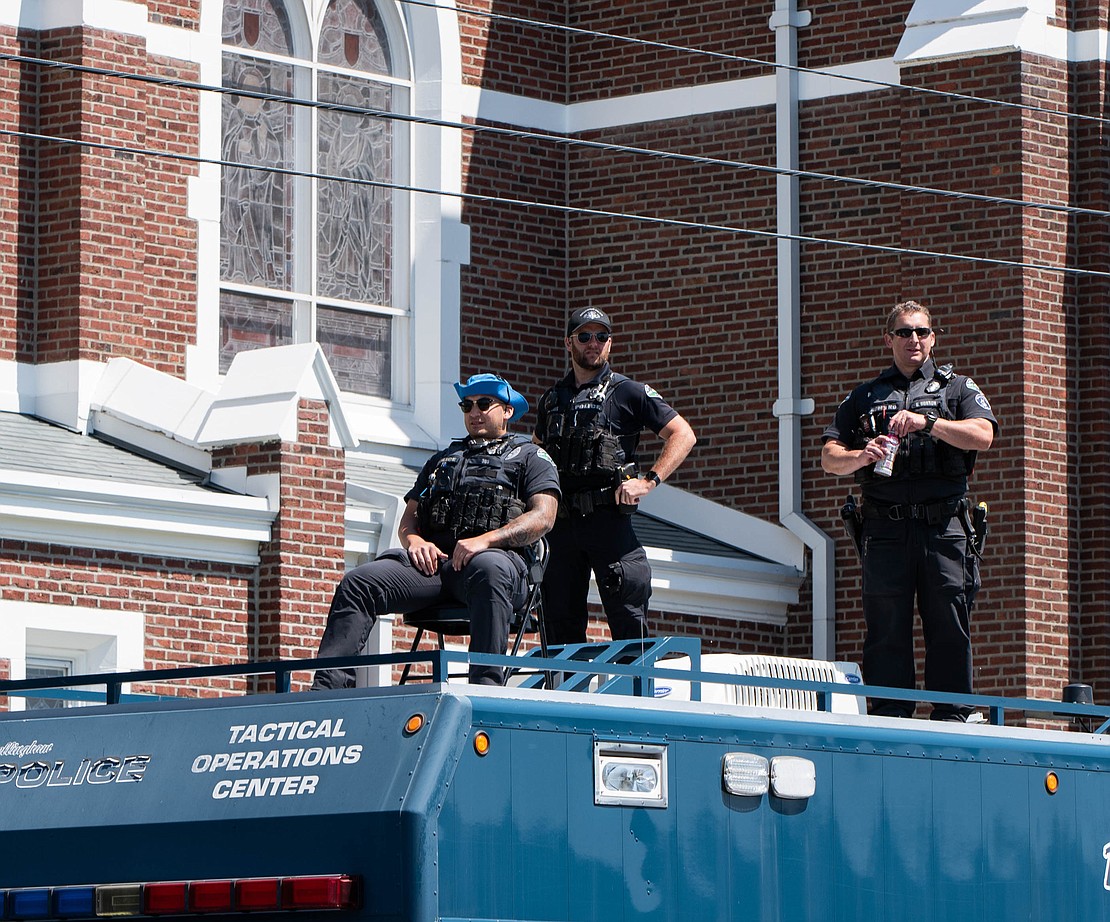 Police officers observe the parade from atop a tactical operations center vehical.