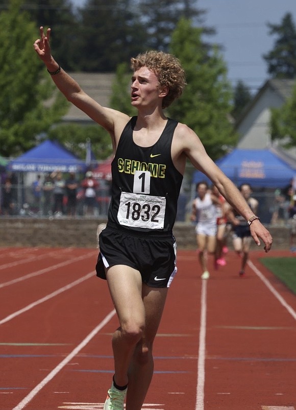 Sehome’s Zack Munson holds up three fingers after winning his third state track title in the 3200-meter run.