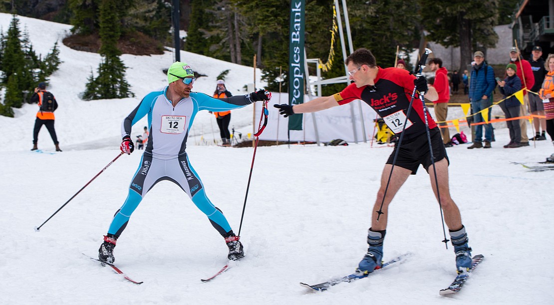 Brian Gregg, left, of Boomer's Drive-In, hands off to Calvin Collander to begin the downhill ski leg.