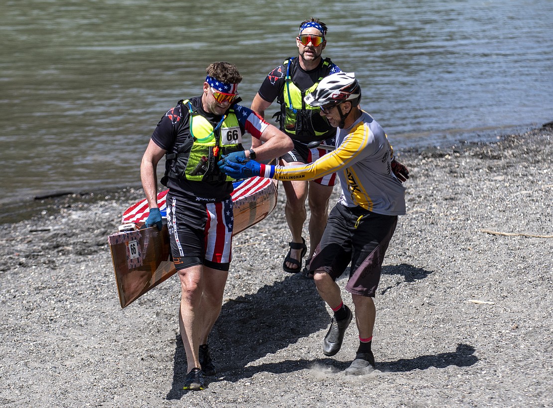 Canoeists of Greatest American Heroes hand off the timing chip to cyclocross racer John Pitton, right, after battling the Nooksack River for 18.5 miles.