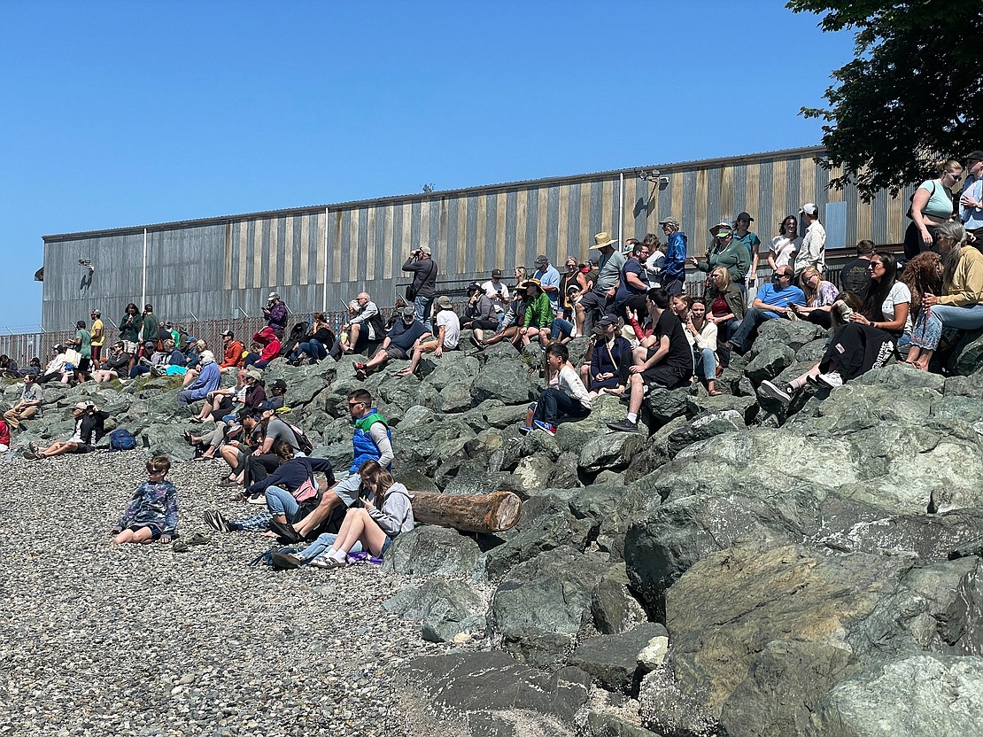 People gather on the rocks in Fairhaven to watch the sea kayakers paddle in to land.