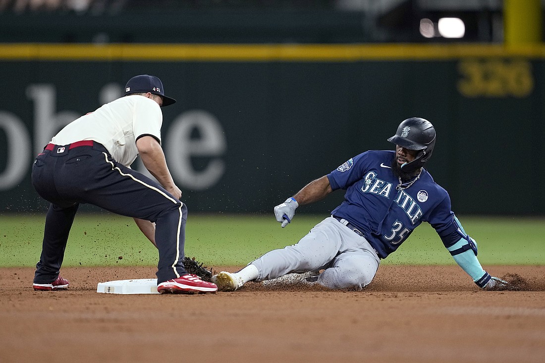 Texas Rangers shortstop Corey Seager, left, reaches down to tag out Seattle Mariners' Teoscar Hernandez (35), who was trying to stretch a single into a double during the third inning of a baseball game Friday, June 2, 2023, in Arlington, Texas.