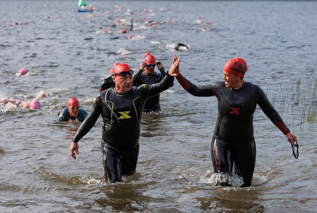 Racers high-five as they exit the water Saturday, June 24, during the Padden Triathlon at Lake Padden Park.