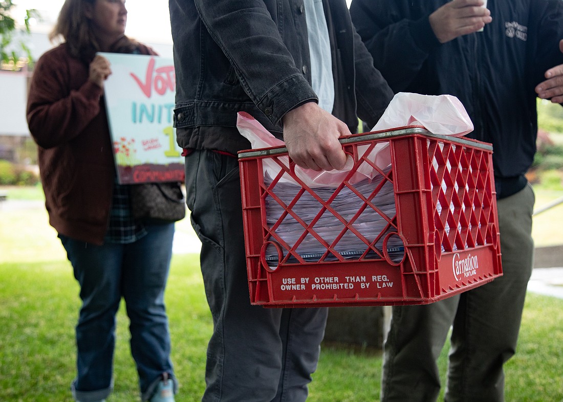 Seth Mangold of Community First Whatcom holds a crate full of petitions Tuesday, June 20, for two initiatives to appear on the Nov. 7 ballot in Bellingham. Initiative 1 would raise Bellingham's minimum wage. Initiative 2 would require landlords to pay renters' relocation costs in some cases.