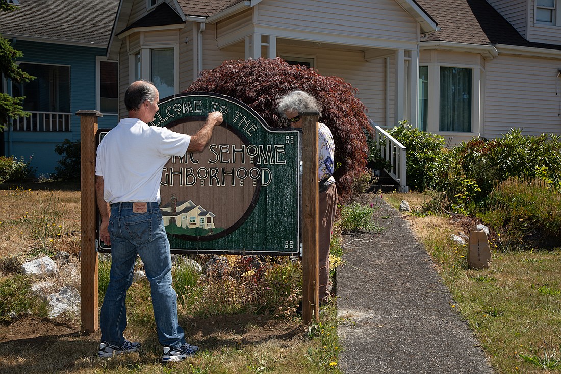 Matt Tellez, left and Katrina Whitefield sage the "Welcome to the Historic Sehome Neighborhood" sign on Thursday, July 13. The sign was nearly destroyed by a drunk driver a few years ago, so the neighborhood held a saging ceremony to expel the bad energy and hopefully protect it.