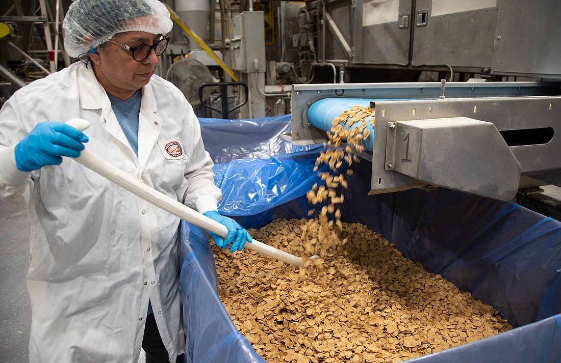 Rachpal Kaur stirs a batch of Heritage Flakes cereal as it pours off the conveyor belt July 13 at the Nature's Path Organic Foods manufacturing facility in Blaine. About a third of the company's employees worldwide are in Whatcom County.