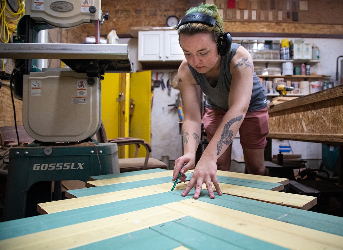 Design build program manager Myra Volkmann builds a garden bench out of reused green and yellow wooden slats on Thursday, Aug. 3 at The RE Store. The shop provides recycled materials for projects and also builds furniture to sell.