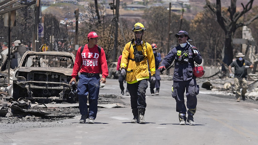Members of a search-and-rescue team walk along a street Saturday, Aug. 12 in Lahaina, Hawaii, following heavy damage caused by wildfire.