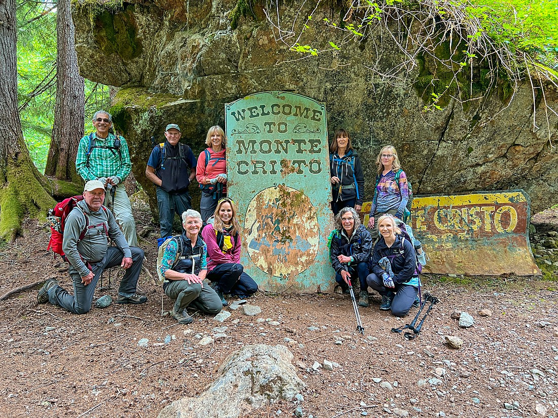 A group of Bellingham hikers, including Elliott Almond (back row, second from left), stop June 14 next to the old sign welcoming visitors to the mining town of Monte Cristo.