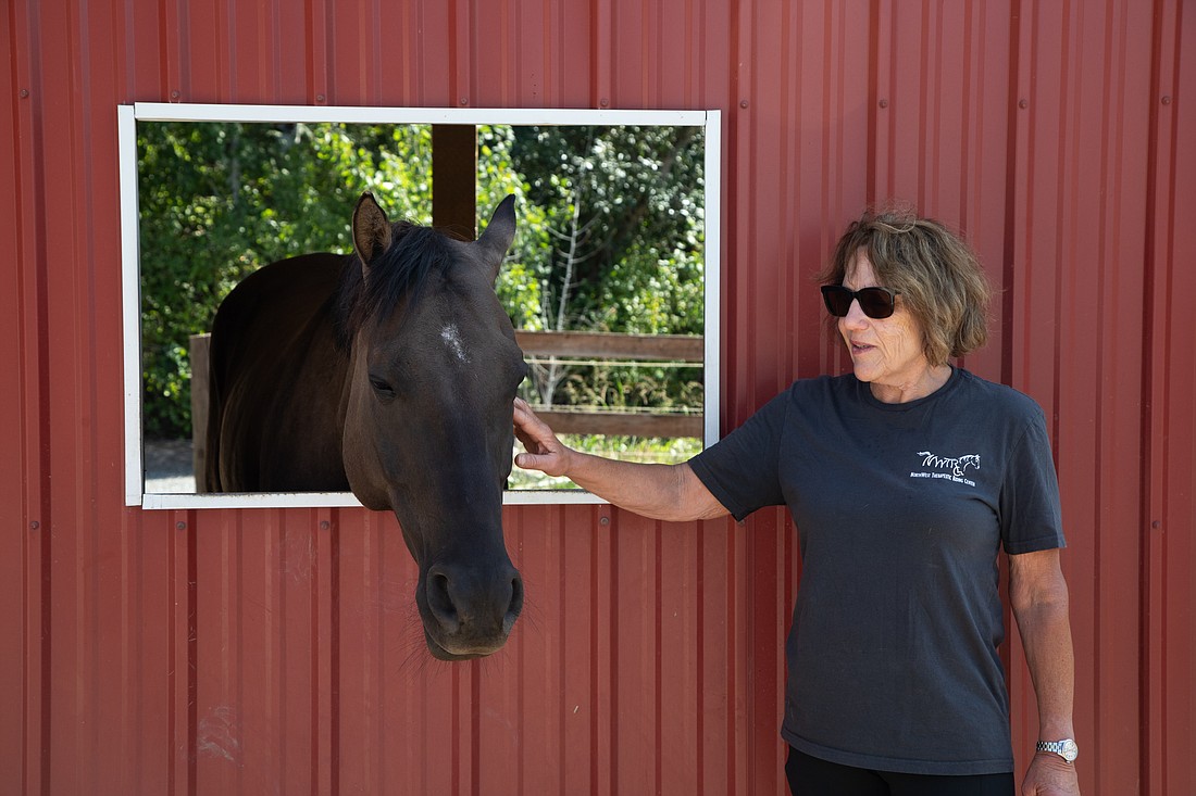 Northwest Therapeutic Riding Center founder Julia Bozzo pets 5-year-old Bruce Aug. 12 at the riding center. Bozzo opened the center in 1993 and has given hundreds of lessons to people with disabilities.