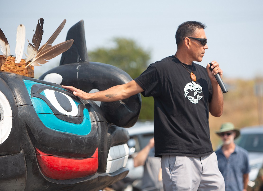 W'tot Lhem, Jay Julius, places a hand on a totem while welcoming the crowd. The totem, carved by the Lummi Nation's House of Tears Carvers, was initially going to be installed at Jackson Beach to help raise awareness of Tokitae and climate change, but instead was installed Sunday, Aug. 27 to honor the orca's life and grieve her death.