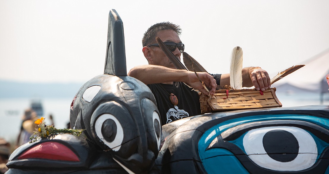 W'tot Lhem, Jay Julius, places a basket with old eagle feathers on the totem.