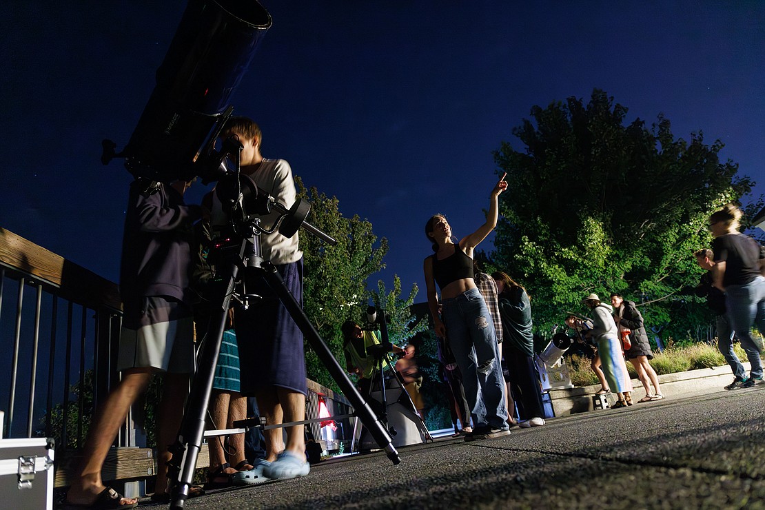 Elie Bassett points out Saturn to her Western Washington University cross-county teammates as they look at the moon and Saturn through telescopes owned by members of the Whatcom Association of Celestial Observers.