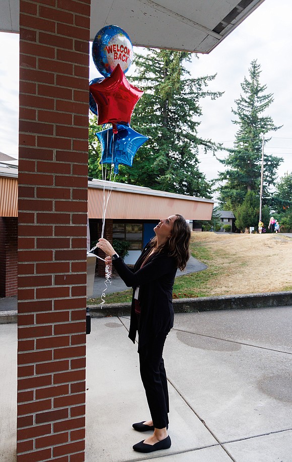 To welcome students on the first day of school, Teacher on Special Assignment (TOSA) Rayna Brandon ties balloons out front at Silver Beach Elementary.