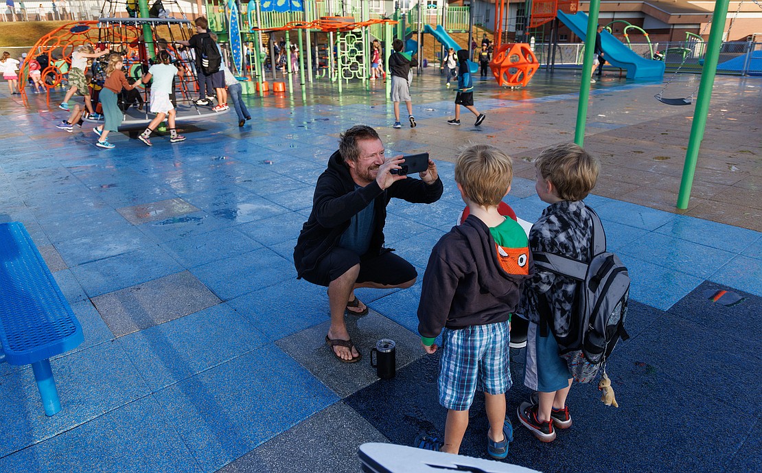 Grant Gunderson photographs his son Stian and a friend at the new playground before leaving.