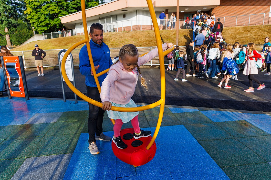 As students head into the building, Jon Falcon spins daughter Amelia one more time in the new inclusive playground before classes start.