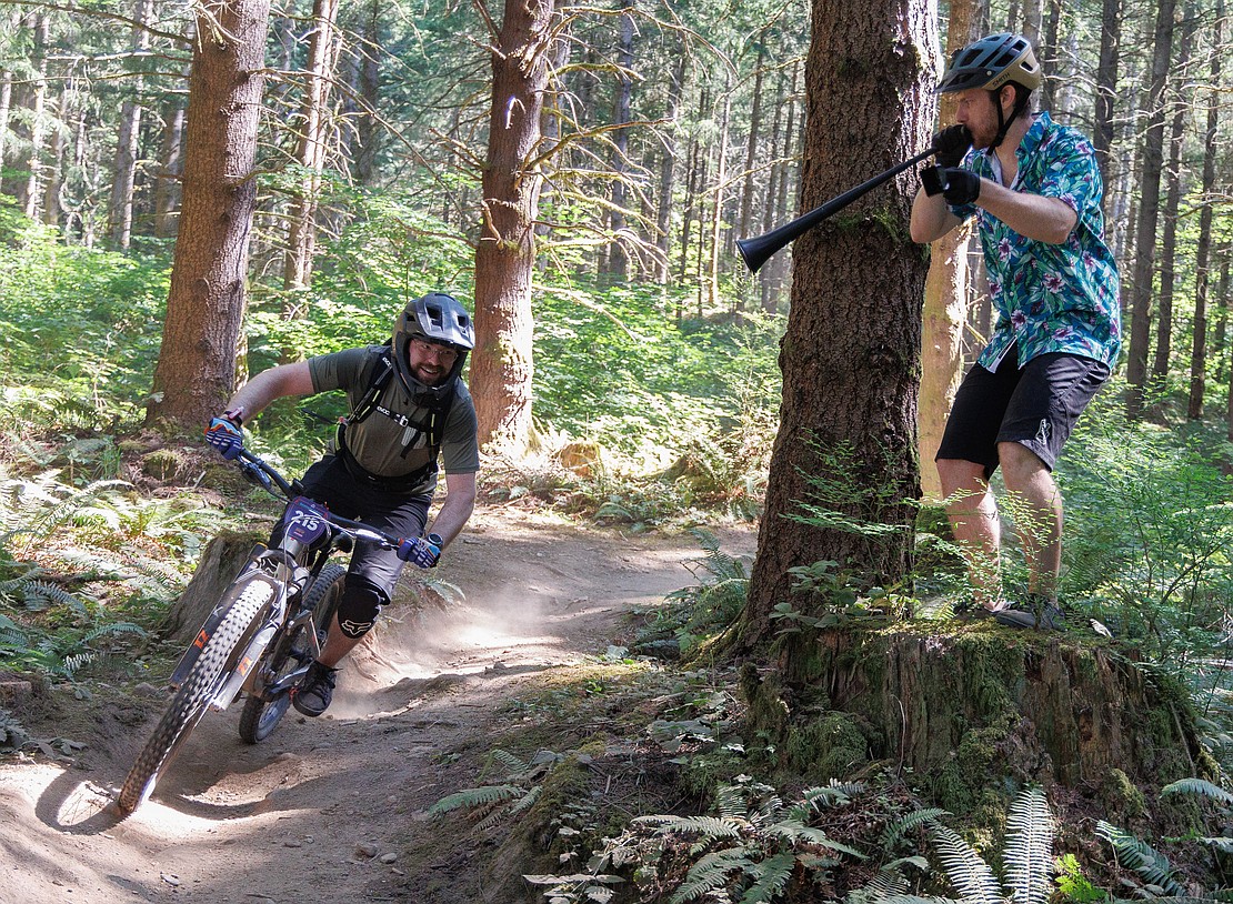 Dallan Pickard blows a vuvuzela and rings a cowbell as racers go by July 15 in the Galbraith Mountain Enduro race during the Northwest Tune-Up Festival.