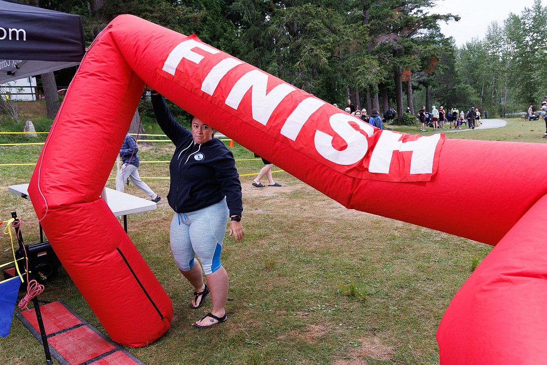 Chrissy Pernevi holds up a deflating finish line for arriving runners June 24 at the Lake Padden Triathlon.