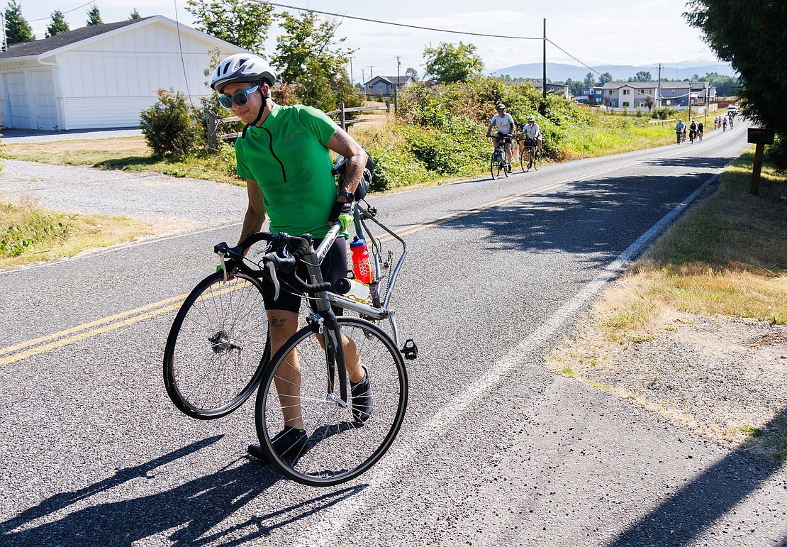 Suffering a flat tire, James Sceshulte walks his bike and wheel to a nearby rest station during the July 22 Tour De Whatcom. Scechulte completed the 44-mile course after getting the flat fixed.