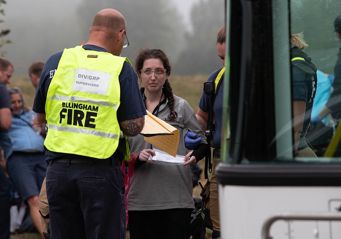 A volunteer crash "victim" shows a card that lists their symptoms to a supervisor before getting on a WTA bus to be transported to the hospital.