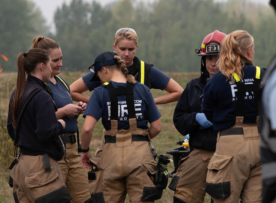 Firefighters talk with each other after wrapping up their responsibilities during the emergency exercise at Bellingham International Airport on Friday, Sept. 8, 2023.