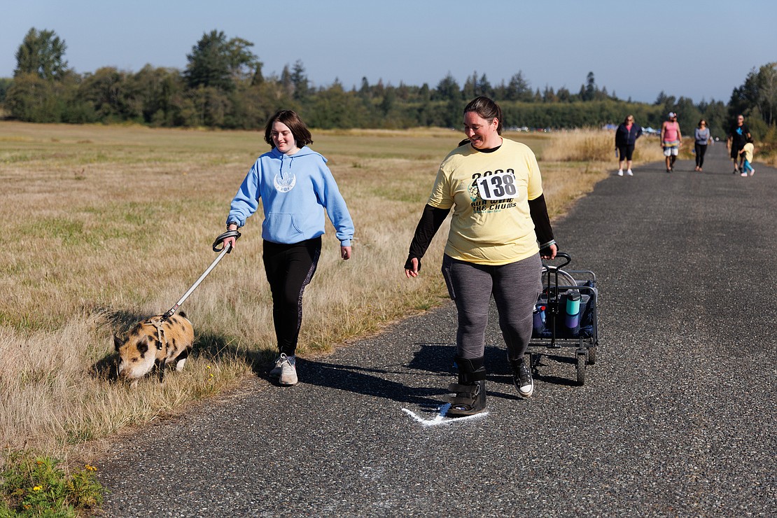Opal Warlock, left, walks with Phoebe, a Kunekune pig, while Suzanne Warlock walks with two cats in a cart.