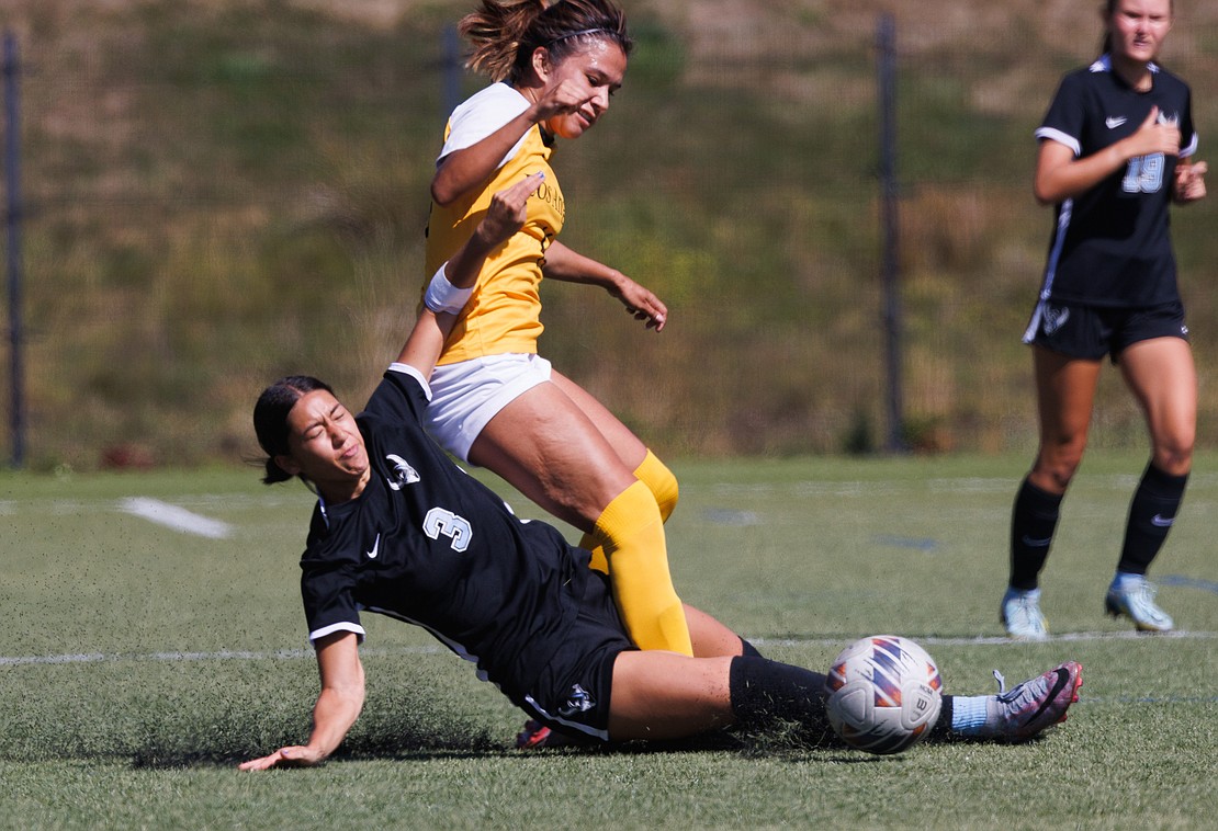 Western Washington University's Mini Rauch slides under a Cal State Los Angeles player while kicking the ball away.