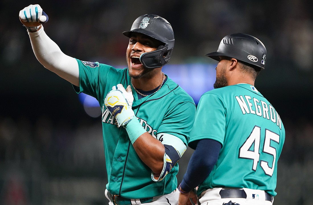 Seattle Mariners' Julio Rodriguez celebrates after hitting an RBI single against the Los Angeles Angels during the fourth inning of a baseball game, next to first base coach Kristopher Negrón (45) on Tuesday, Sept. 12, 2023, in Seattle.