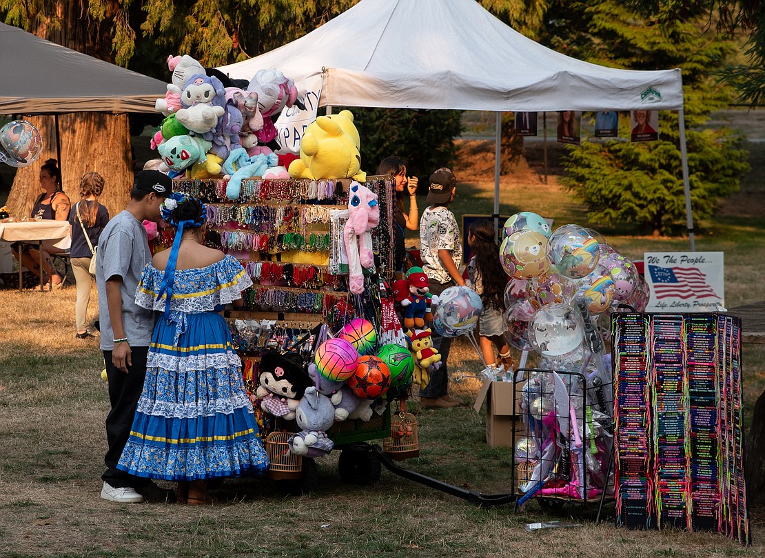 Two festivalgoers browse a booth selling colorful bracelets.