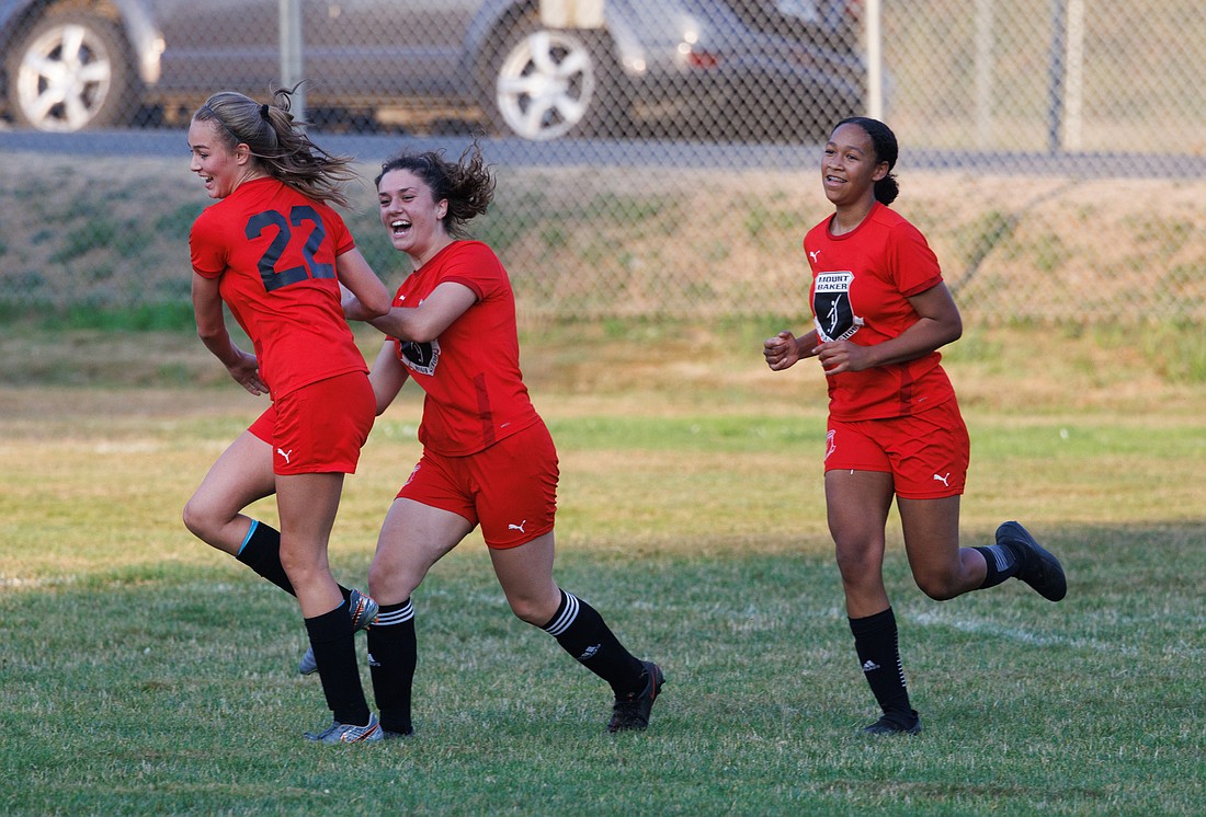 Mount Baker's Lillian Petersen, middle, celebrates her goal Sept. 26, 2022, with Tyler Olson, left, and Faith Wilson during a game against Nooksack Valley.