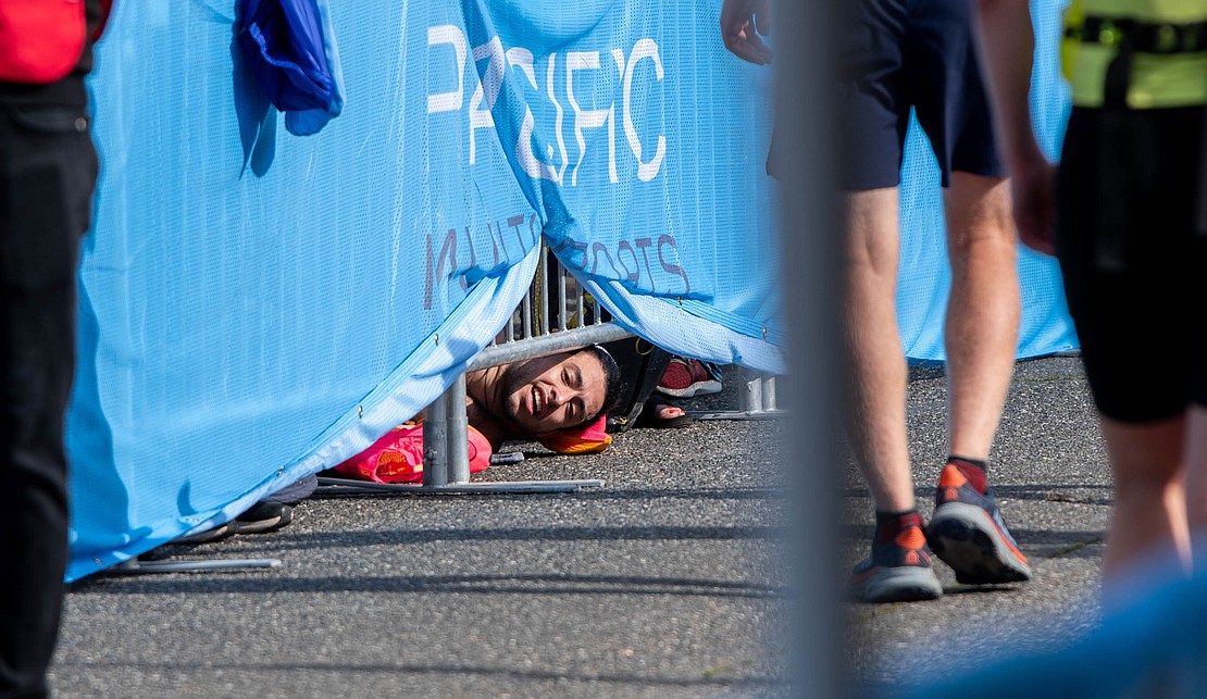 Ian Cervantes cheers on runners from under the barricade at the finish line as he recovers from his 3:19:15 marathon run on the ground.