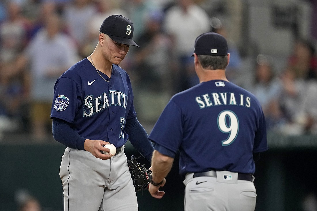 Seattle Mariners starting pitcher Bryan Woo, left, turns the ball over to manager Scott Servais (9) in the fourth inning of a baseball game against the Texas Rangers, Sunday, Sept. 24, 2023, in Arlington, Texas.