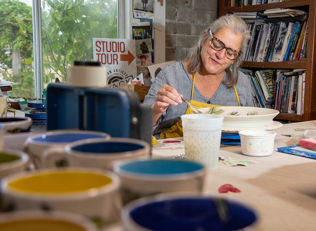 Ann Marie DeCollibus glazes a plate in her home studio in Ferndale in October 2022. DeCollibus is a member of the Whatcom Artists of Clay & Kiln (WACK) and her studio will be one of the stops on the WACK Studio Tour happening Nov. 4–5 throughout Whatcom County.