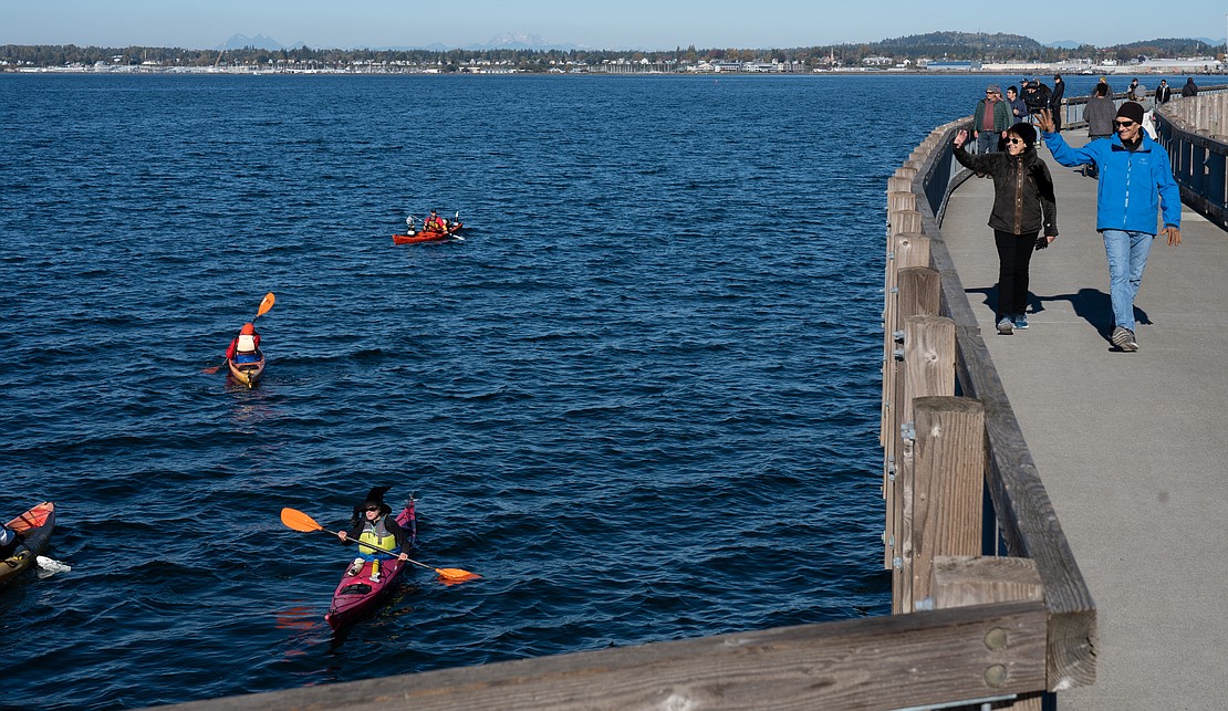 Joe, right, and Leslie Svoboda wave to the kayakers below as they walk Taylor Dock. Although the sun was out, temperatures throughout the day were around 50 degrees Fahrenheit.