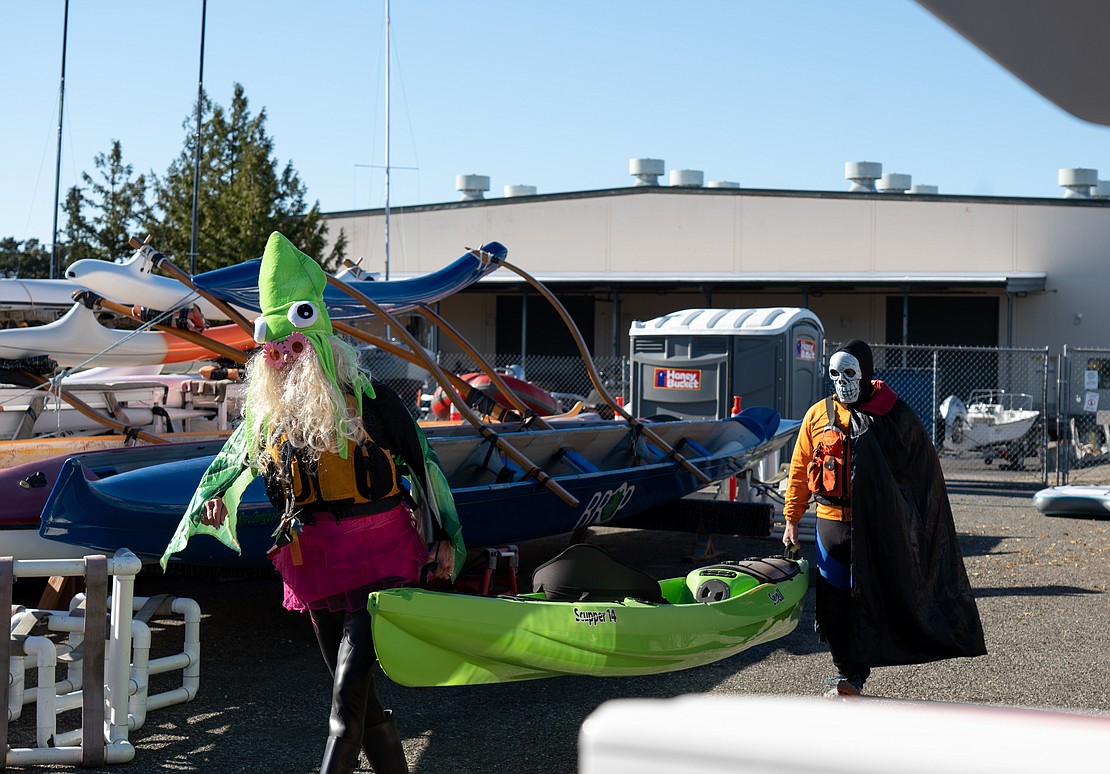 Mickey Middendorf, left, and Dean Kanenaga carry Middendorf's kayak out to the water Saturday, Oct. 28 at the Community Boating Center. "I had to match my kayak," Middendorf said before the Halloween Sea Monsters parade.