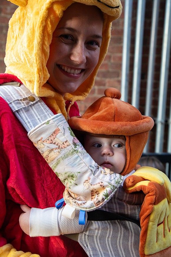 Alexa Stewart as Pooh Bear carries Stevie Stewart, 7 months, who was dressed as Pooh's pot of honey for Halloween.